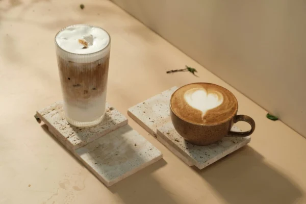 A tall iced latte and a hot latte with latte art displayed on stone coasters, representing the rise of premium and functional coffee in modern cafés.