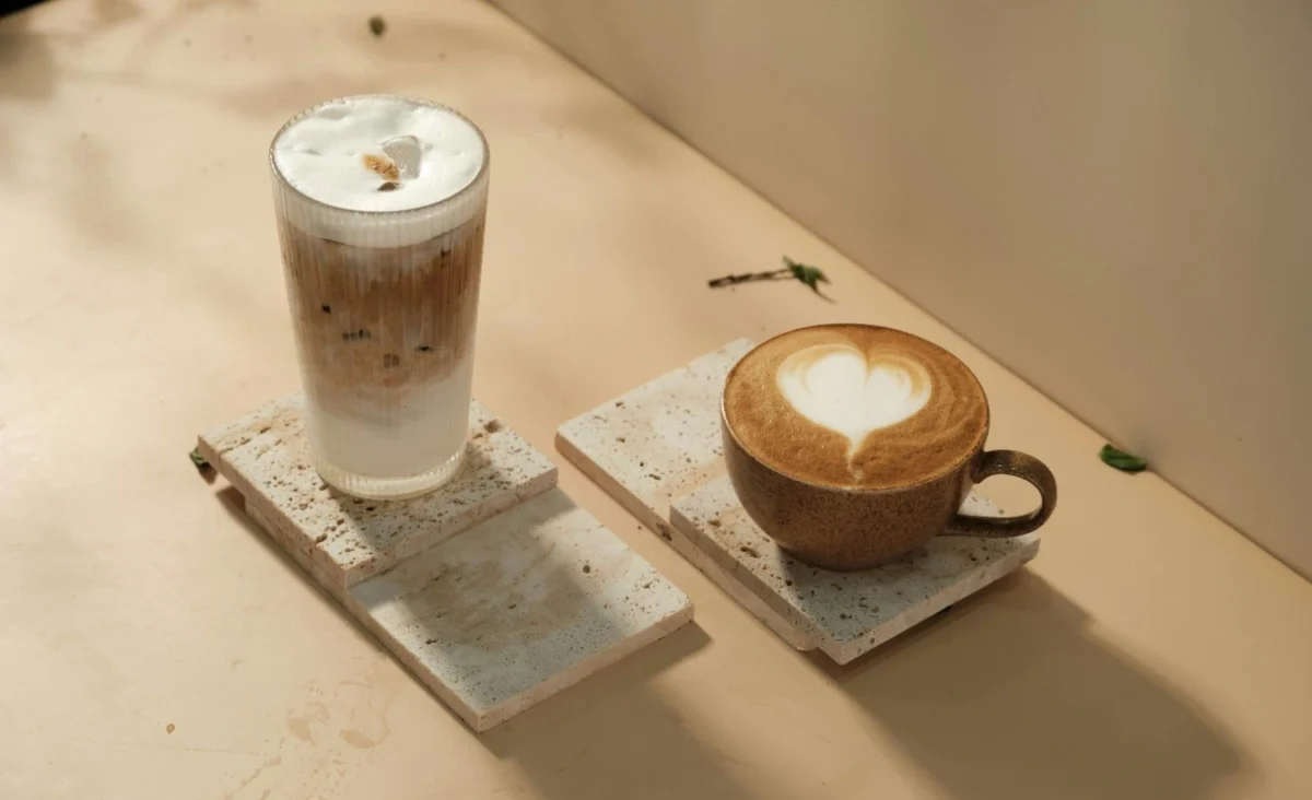 A tall iced latte and a hot latte with latte art displayed on stone coasters, representing the rise of premium and functional coffee in modern cafés.