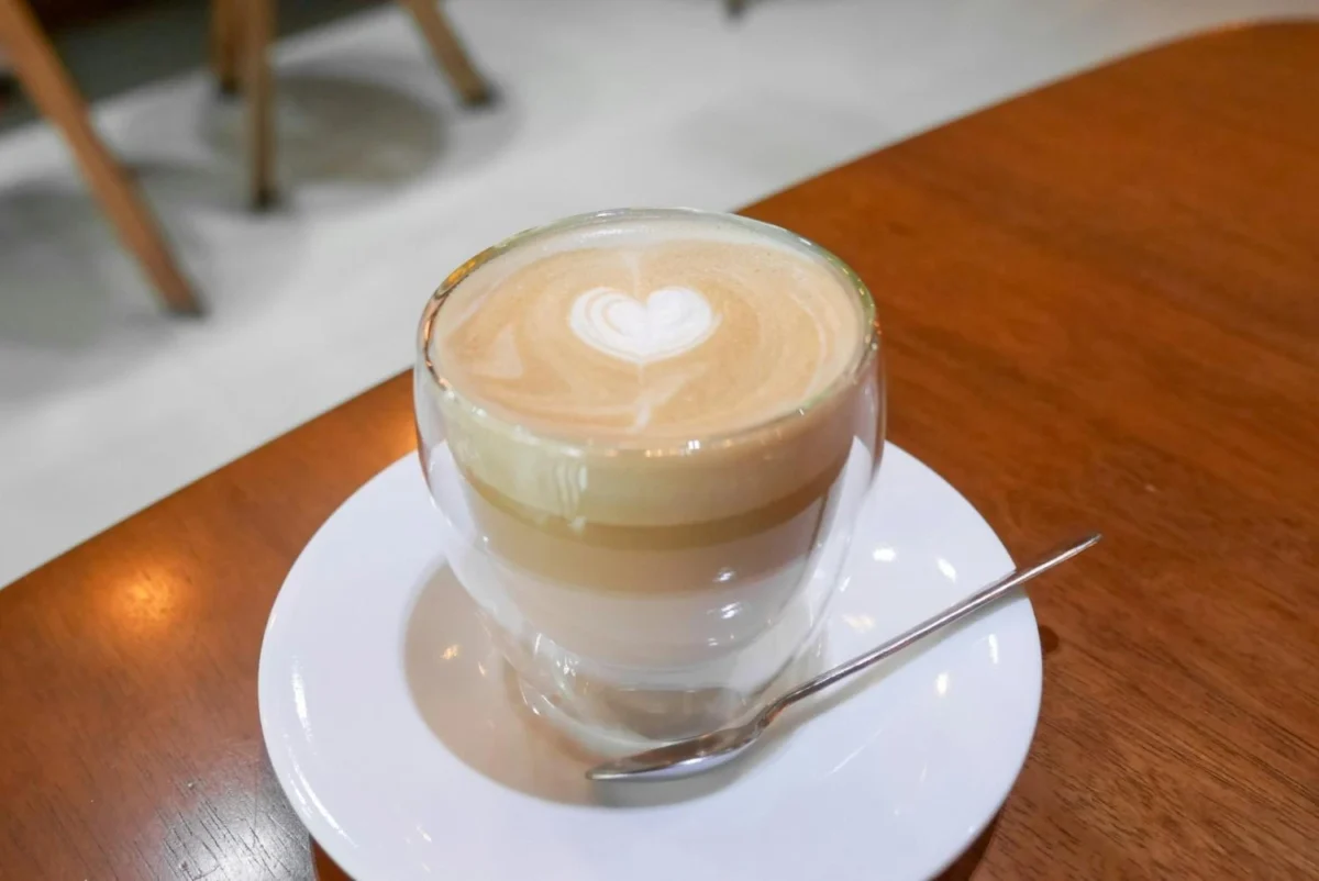 A layered latte with heart-shaped latte art served in a glass cup, illustrating the taste and appearance of modern functional lattes.