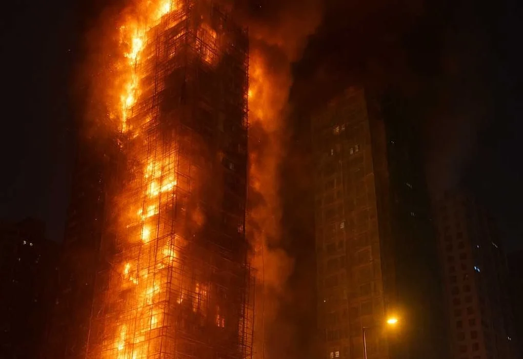 Illustrative AI-generated image of a high-rise building in Hong Kong engulfed in flames at night, with scaffolding burning, thick smoke rising, and fire engines responding below.