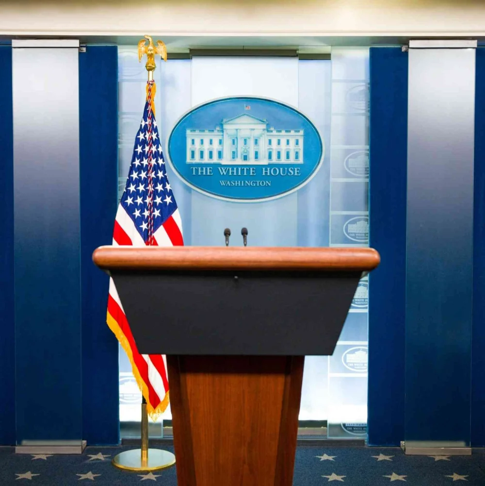 White House press podium with the U.S. flag inside the briefing room in Washington, D.C.
