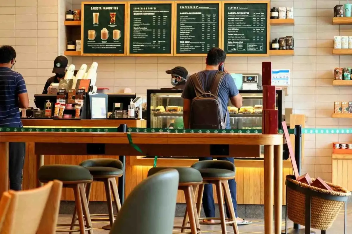 Baristas working behind the counter inside a Starbucks café while customers place orders.