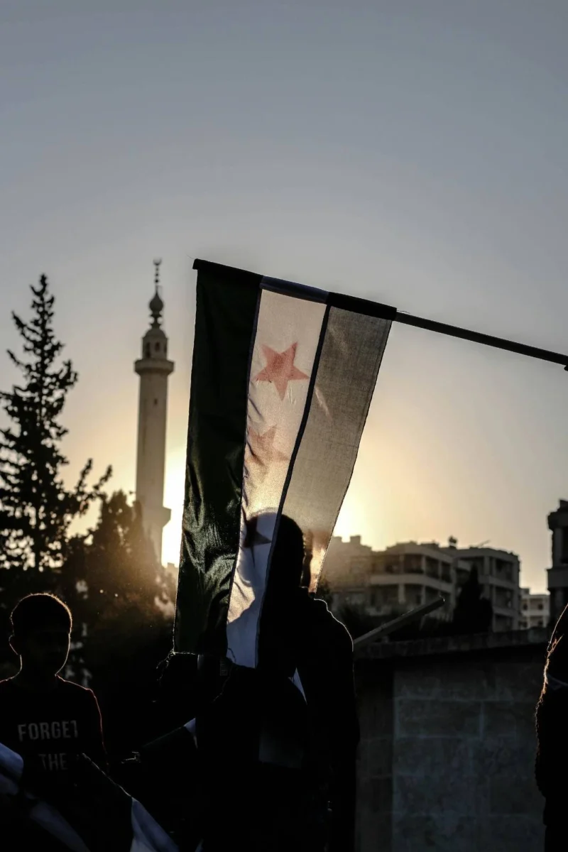 Syrian flag against mosque minaret at sunset in Homs