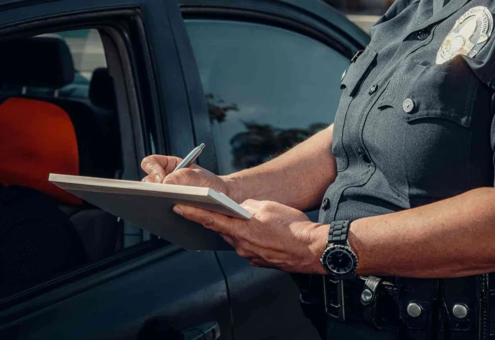 A police officer writes notes beside a patrol vehicle in a generic law enforcement image used to illustrate the Guthrie case.
