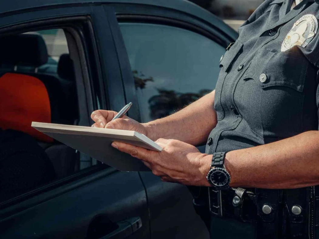 A police officer writes notes beside a patrol vehicle in a generic law enforcement image used to illustrate the Guthrie case.