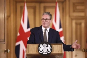 UK prime minister speaking at an official podium with Union Jack flags during a government address