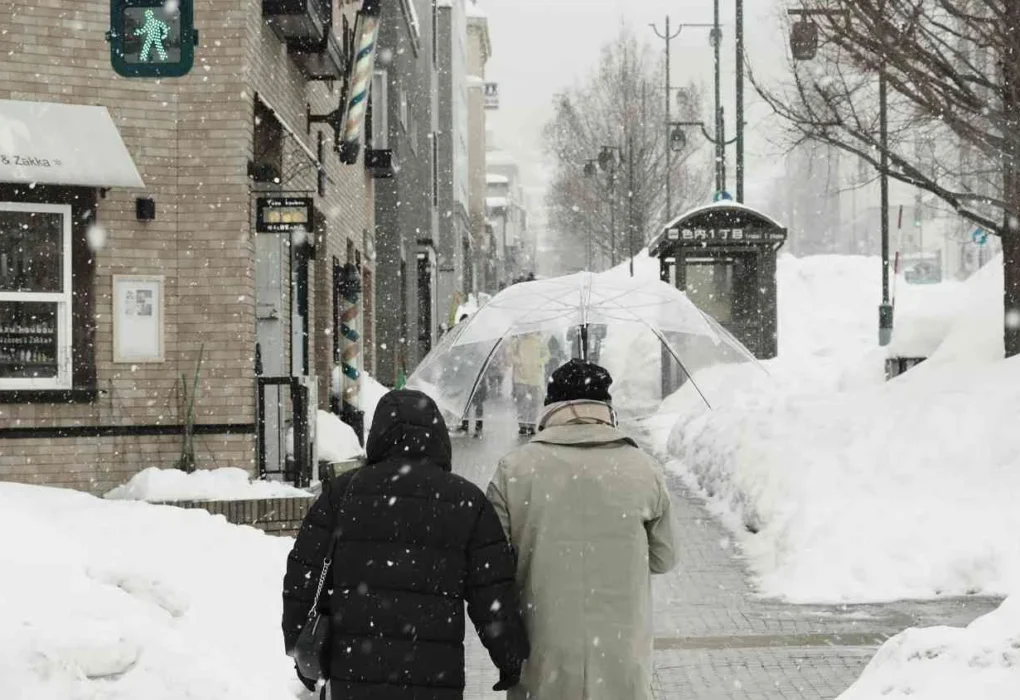 File photo: Pedestrians walking through heavy snowfall under an umbrella during cold UK weather in winter.