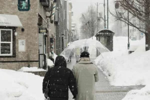 File photo: Pedestrians walking through heavy snowfall under an umbrella during cold UK weather in winter.