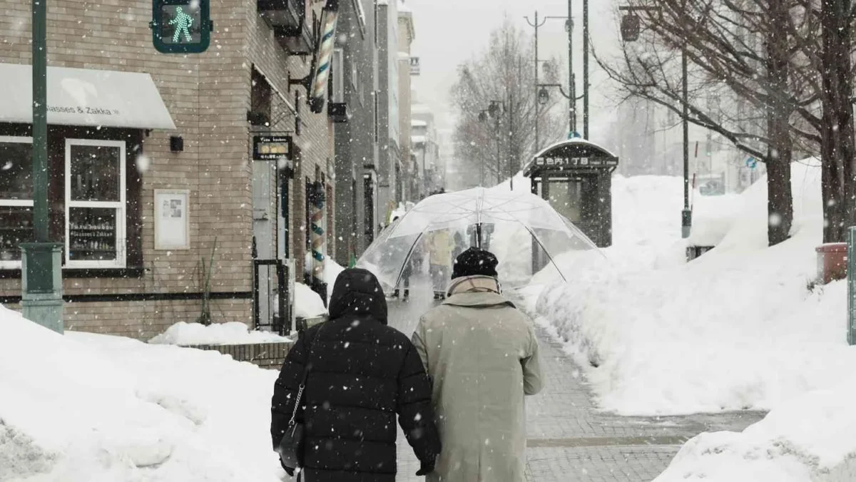 File photo: Pedestrians walking through heavy snowfall under an umbrella during cold UK weather in winter.