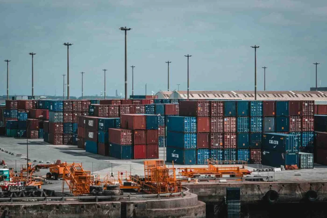 Shipping containers stacked at a commercial port representing US import tariffs and global trade impact